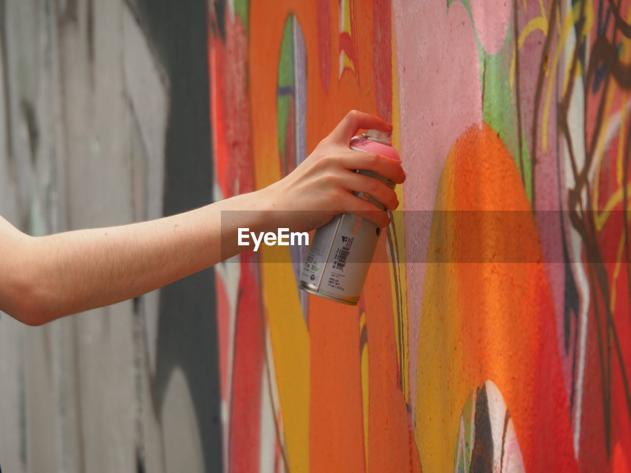 Cropped image of person painting graffiti on wall