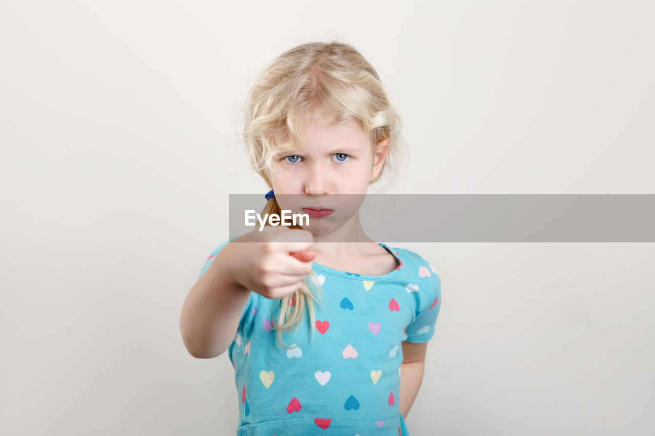 Child girl showing fig sign. kid expressing strong negative emotion