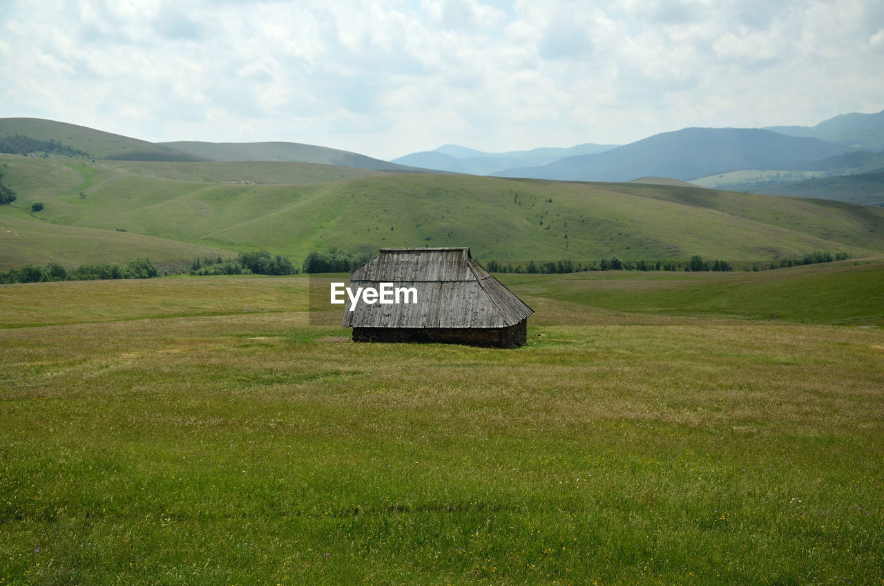 Archaic wood house in green countryside in spring time