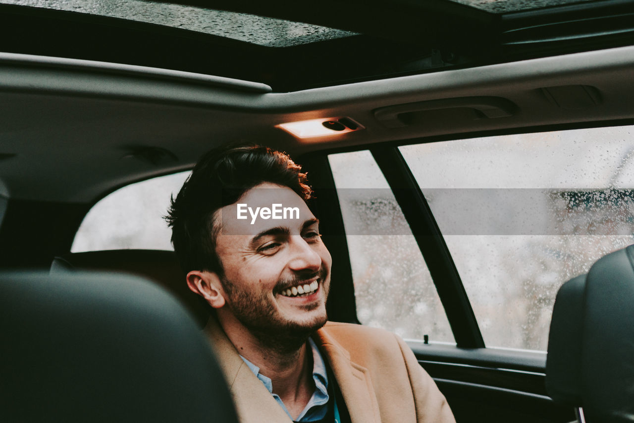 Close-up of happy businessman traveling in car