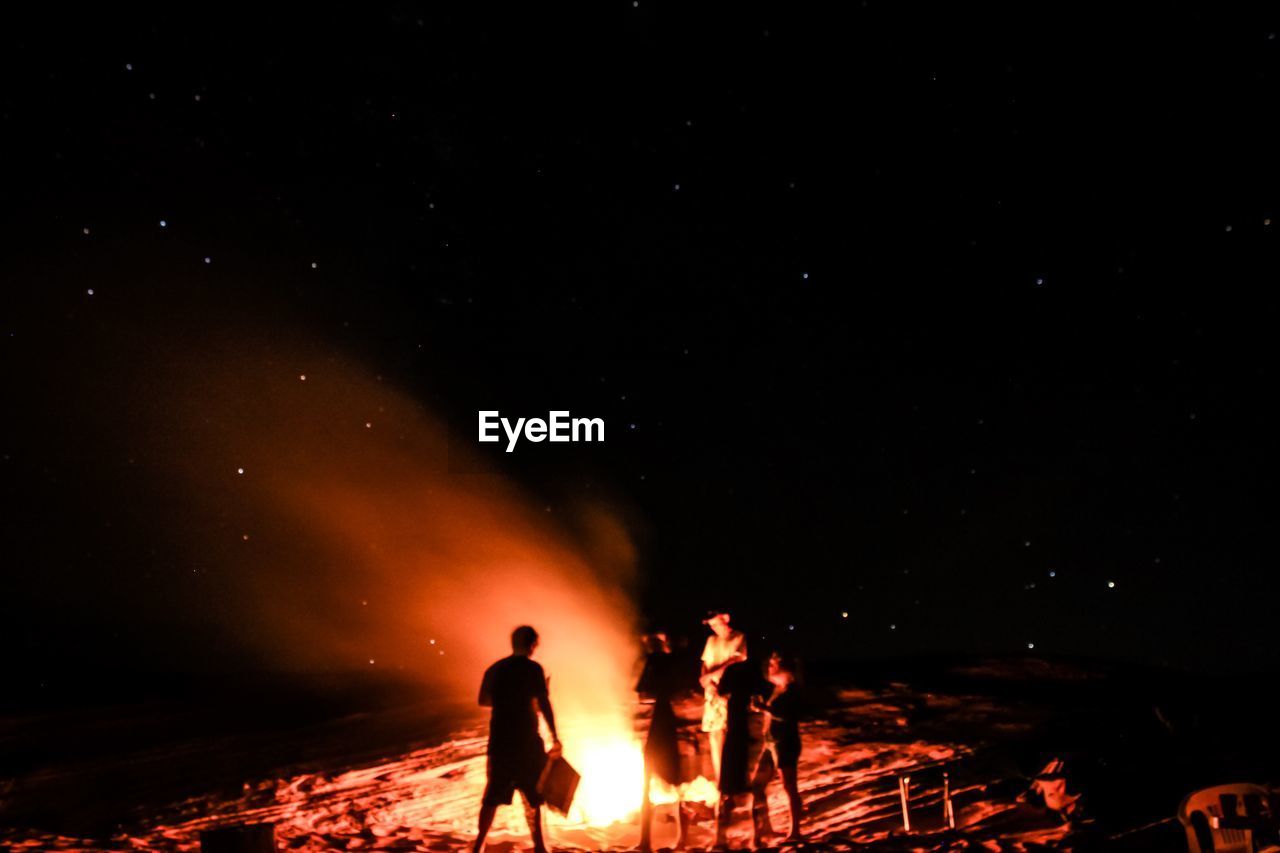 People standing by campfire at field