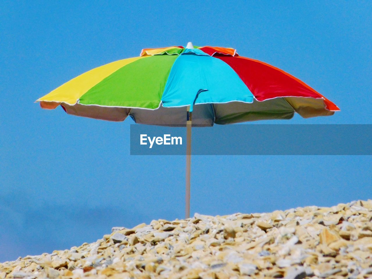 Close-up of umbrella on beach against clear blue sky