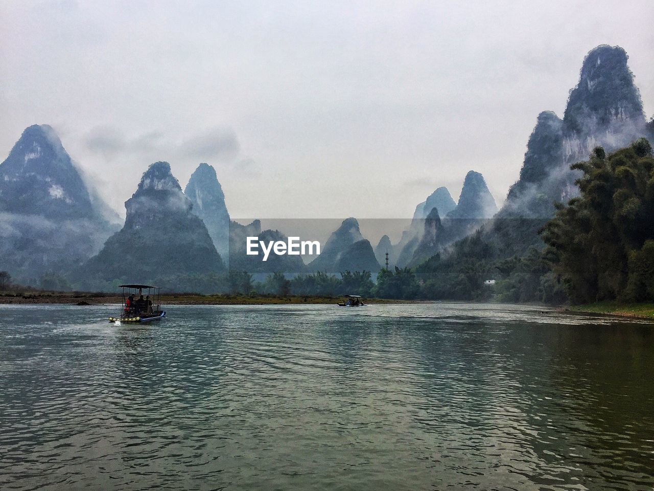 BOATS SAILING ON LAKE AGAINST MOUNTAINS