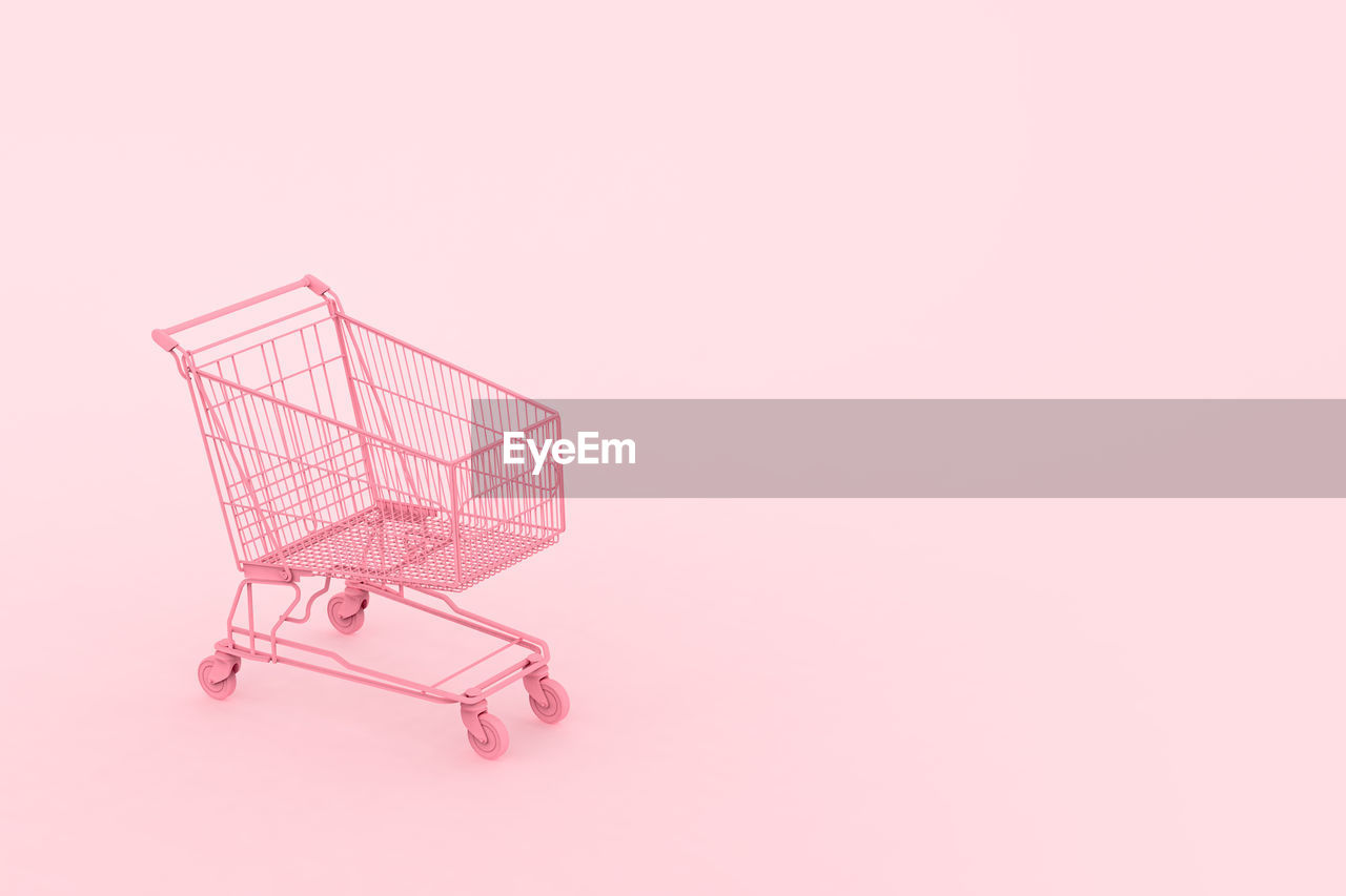 Pastel pink shopping cart on pink background. black friday sales minimalistic concept. shop online