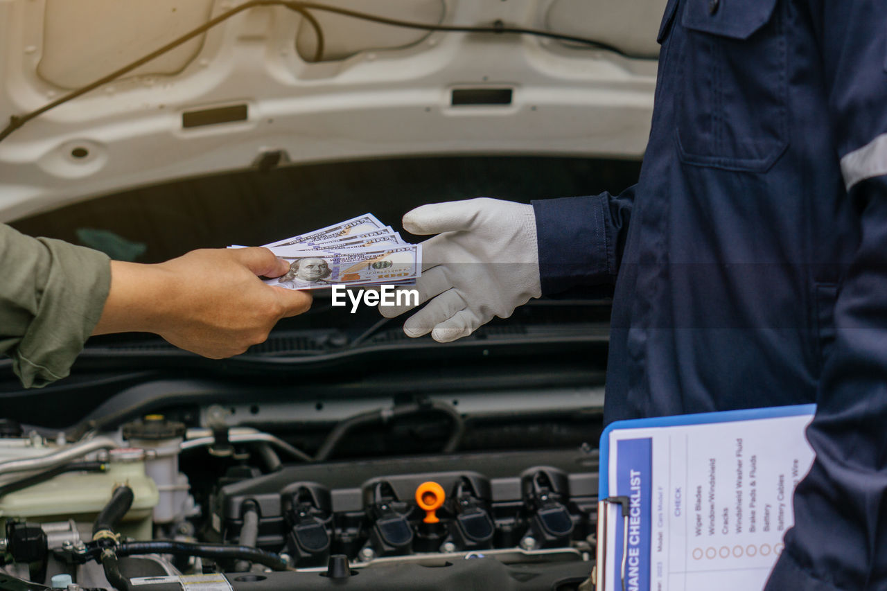 Mechanic man takes cash as payment from customer.after finish checking car system.repair service.
