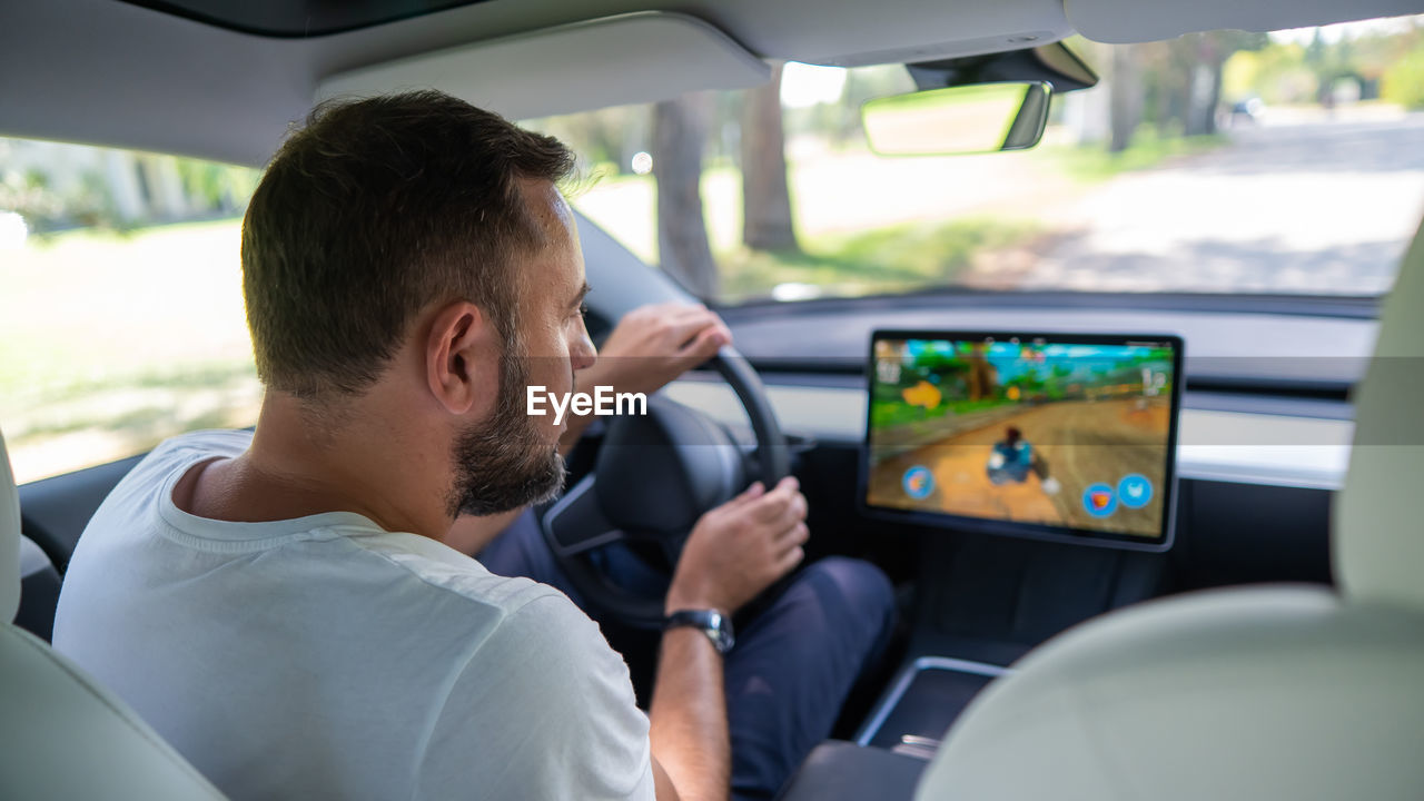 side view of man photographing through window in car