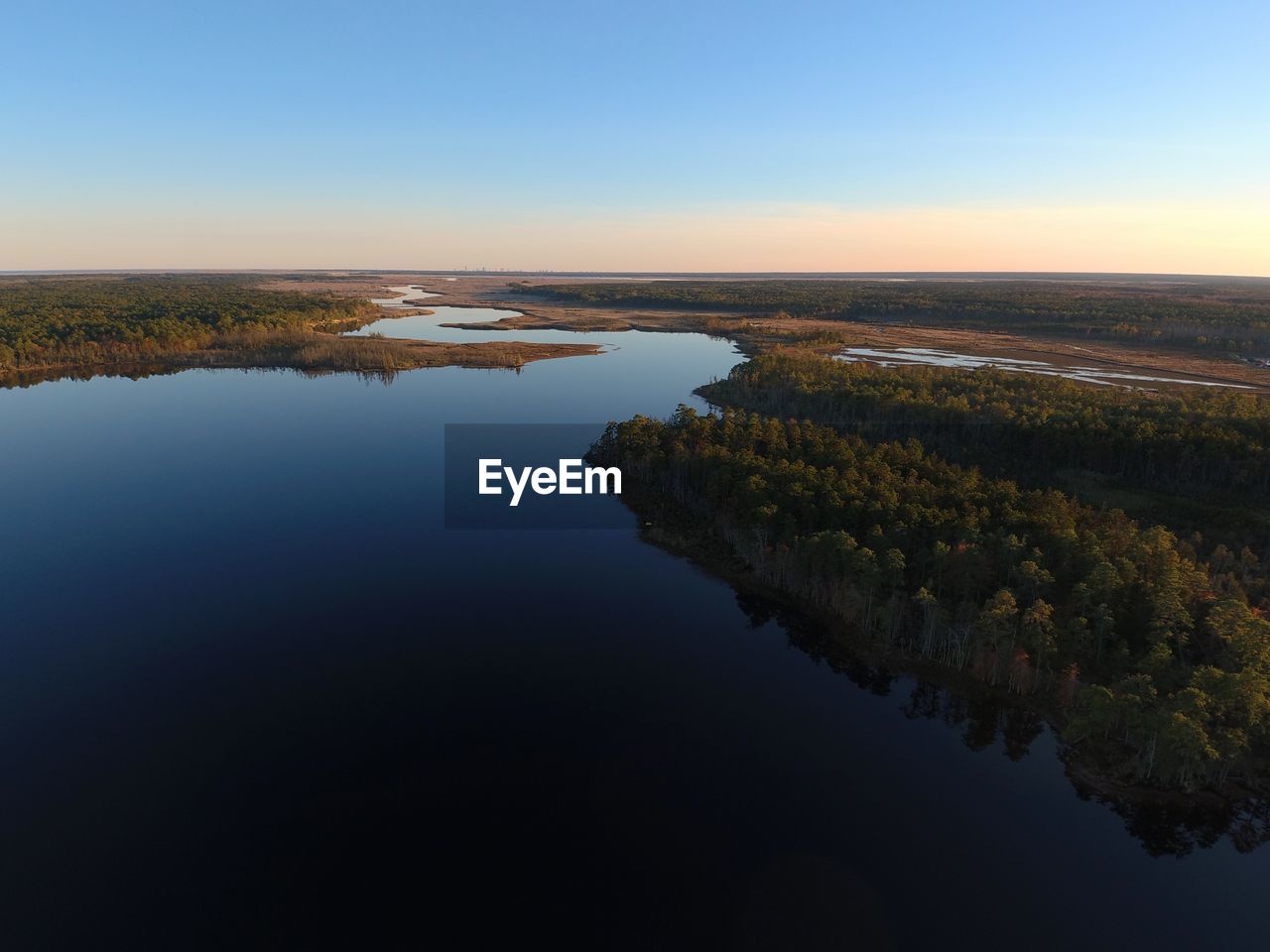 SCENIC VIEW OF LAKE AGAINST CLEAR SKY DURING SUNSET