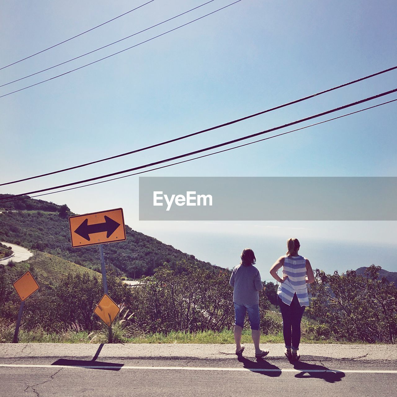 Rear view of friends standing by road sign on footpath