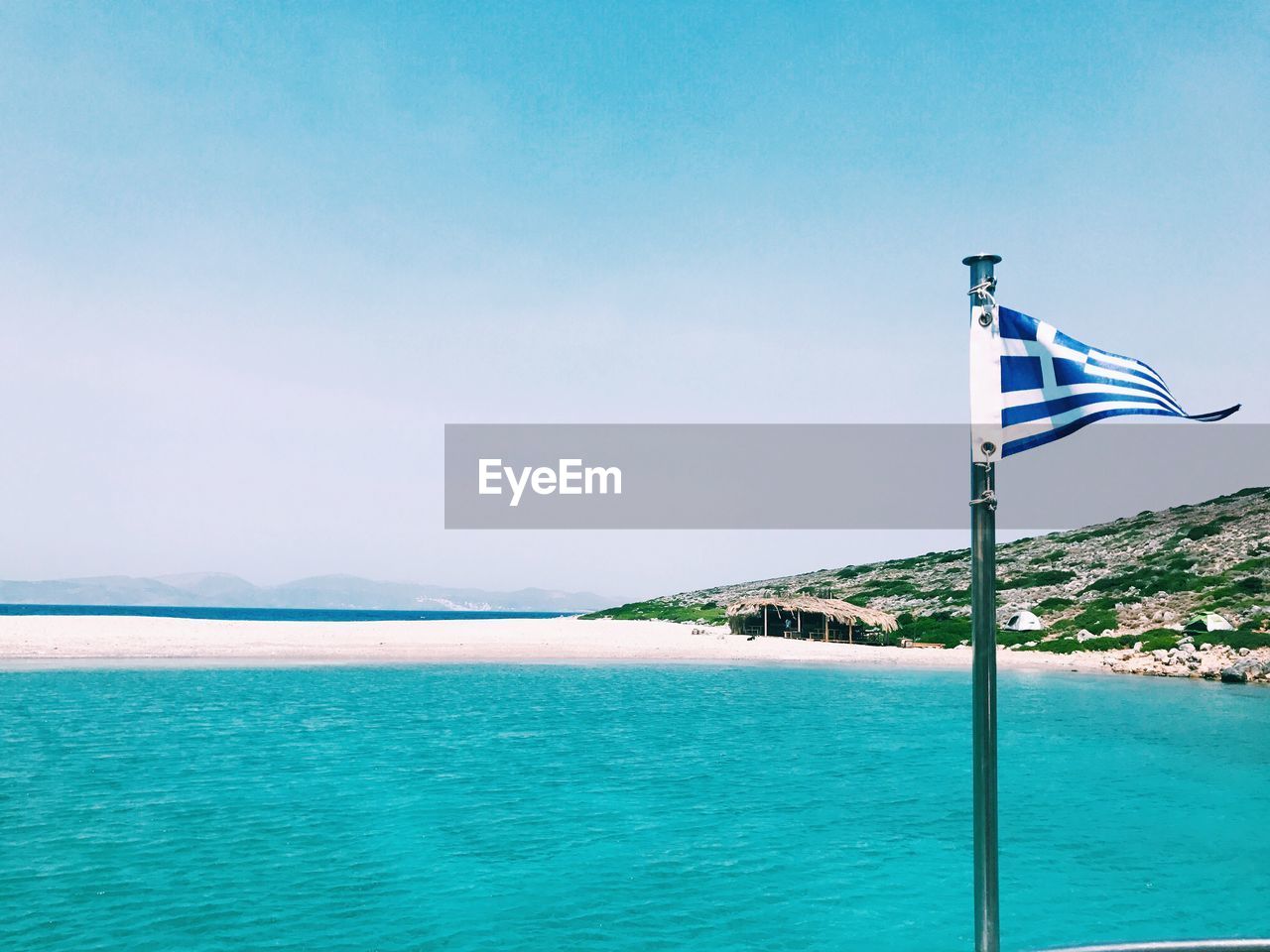 Greek flag in sea against sky