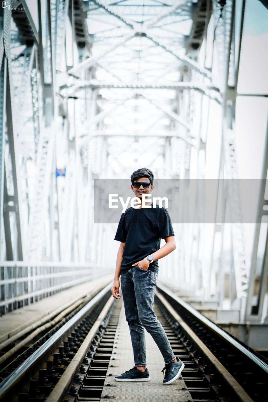 full length of young man standing on railroad station