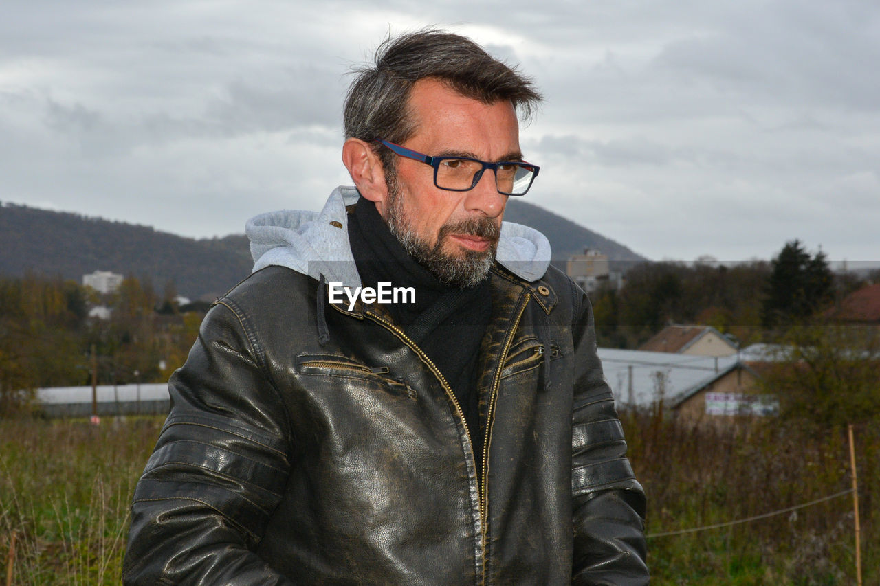 Man looking away while standing against sky