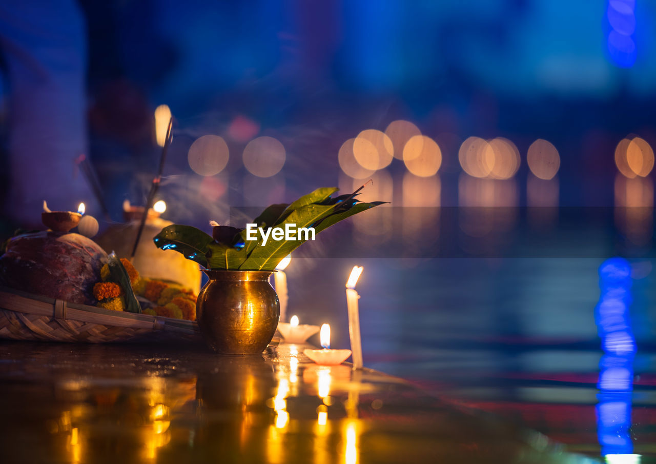 CLOSE-UP OF ILLUMINATED CANDLES ON GLASS