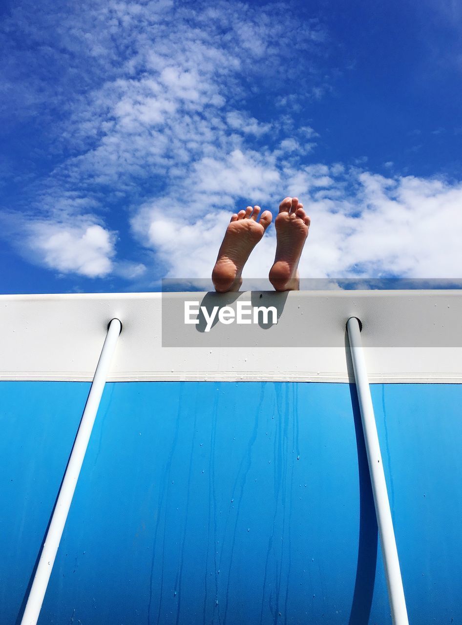 Low section of person resting on boat against sky during sunny day