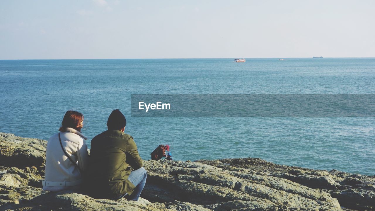 Rear view of people sitting on beach