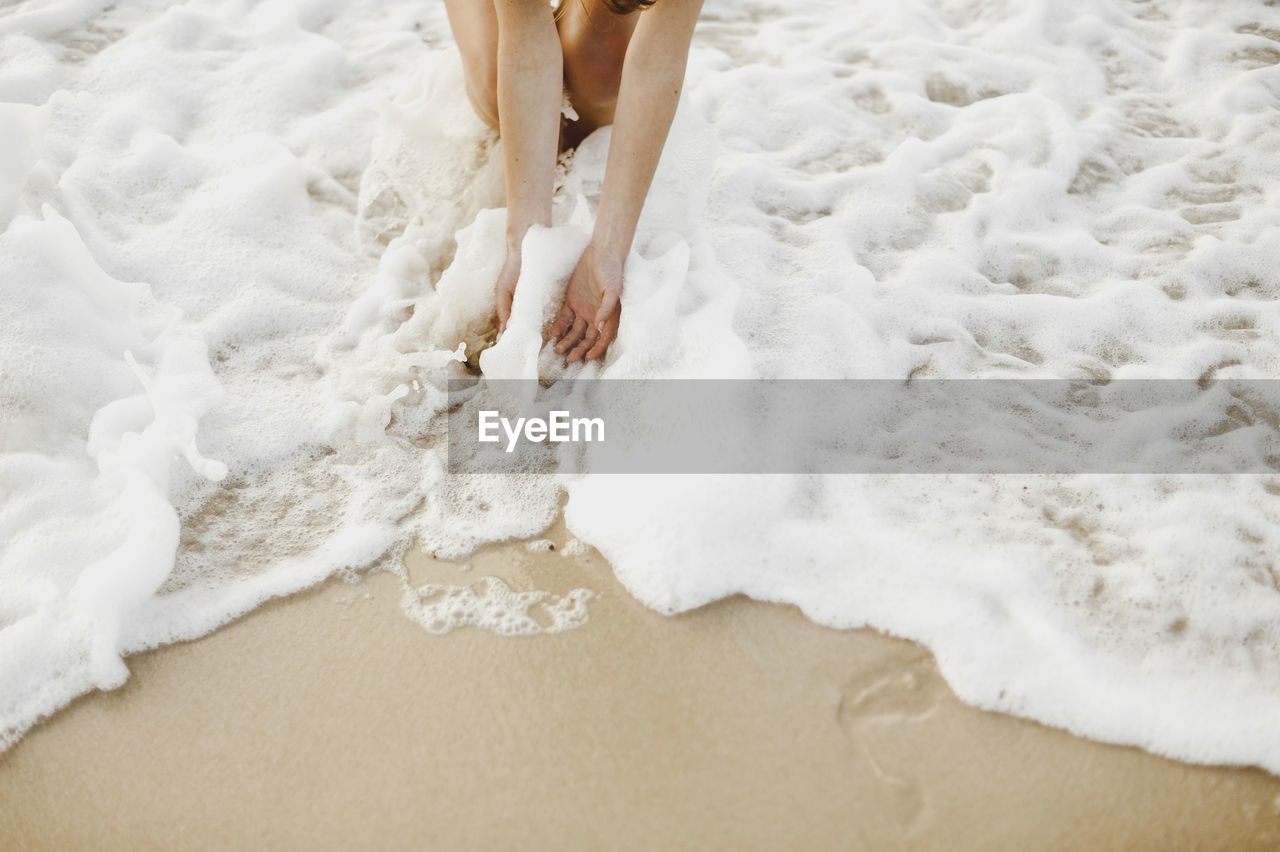 Low section of woman standing on shore at beach