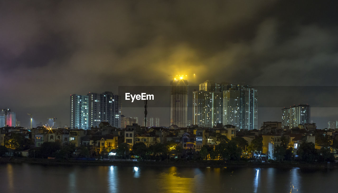 Illuminated buildings in city against sky at night