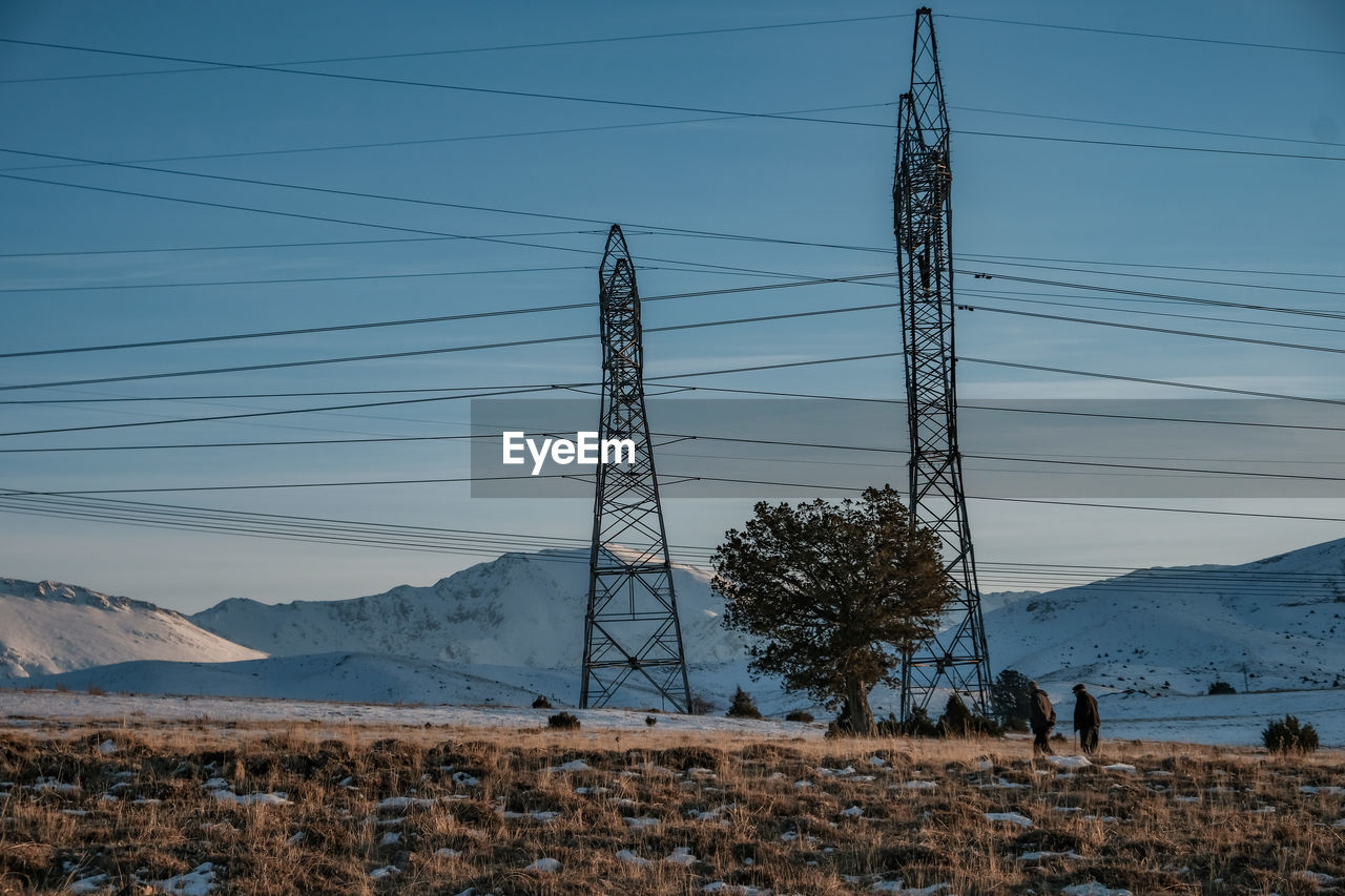 Electricity pylon on field against sky during winter