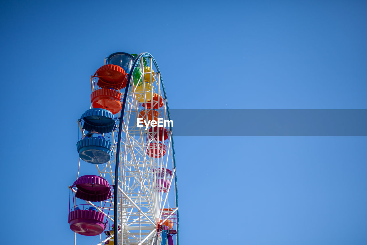 A large ferris wheel against a blue sky. booths with people go up. 