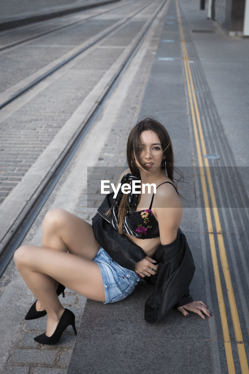 Portrait of young woman sitting on road