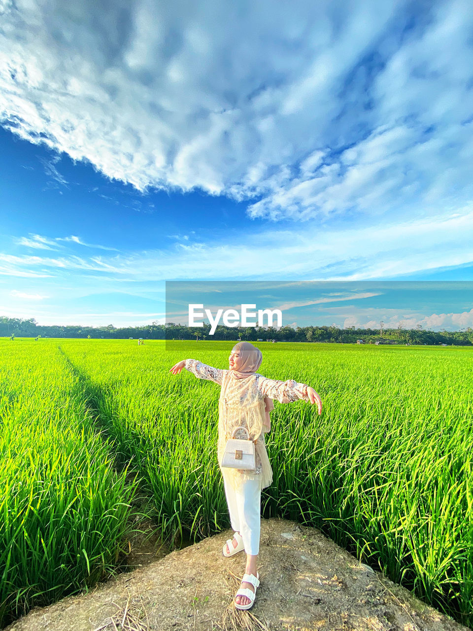 rear view of woman standing on grassy field against sky