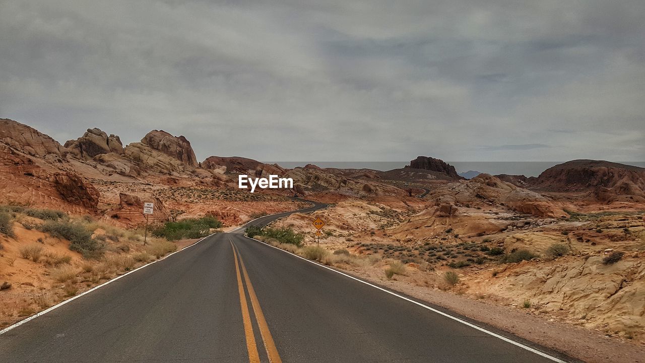 Road leading towards mountains against sky