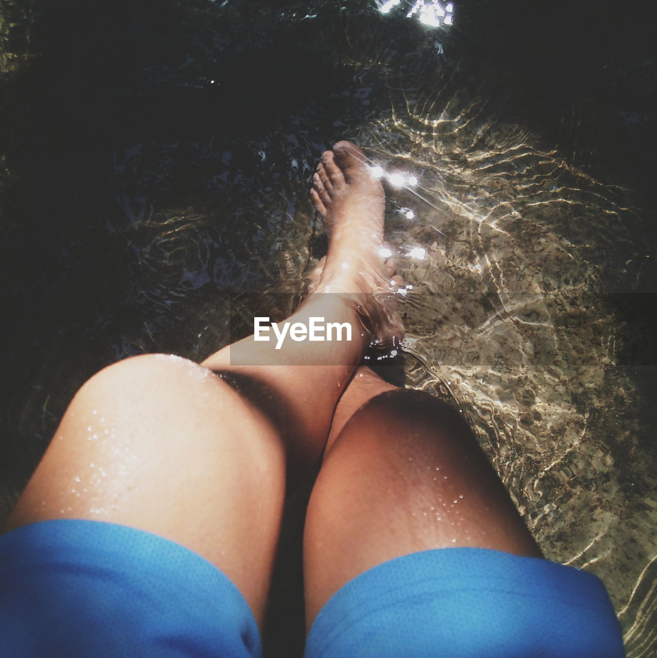 Low section of woman in shallow water at pond