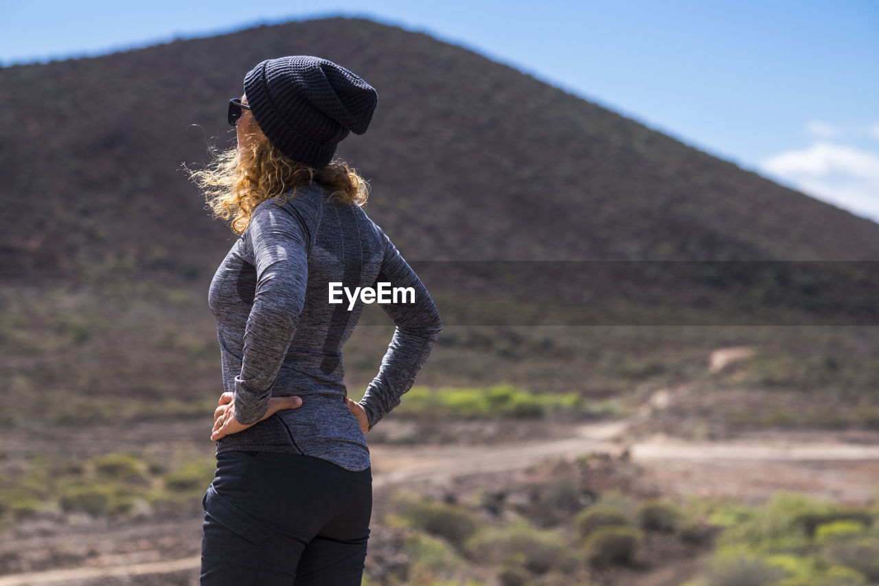 Woman wearing hat while standing against mountain