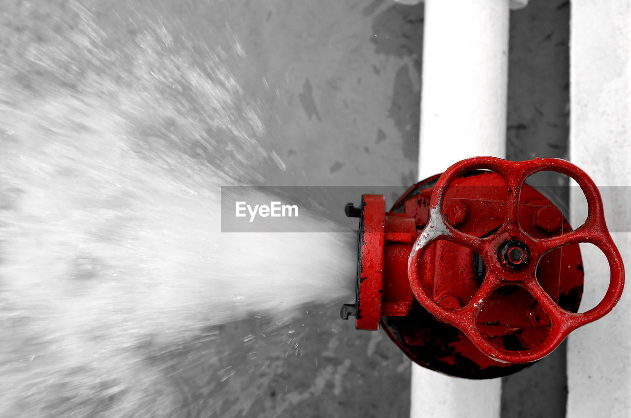 CLOSE-UP OF FIRE HYDRANT AGAINST RED WATER