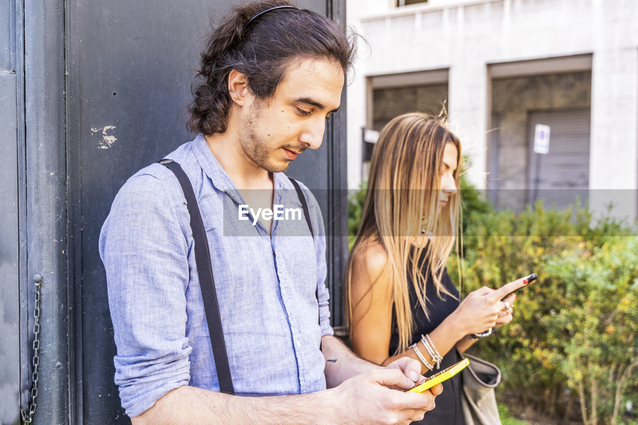 Young couple using smart phone while standing outdoors