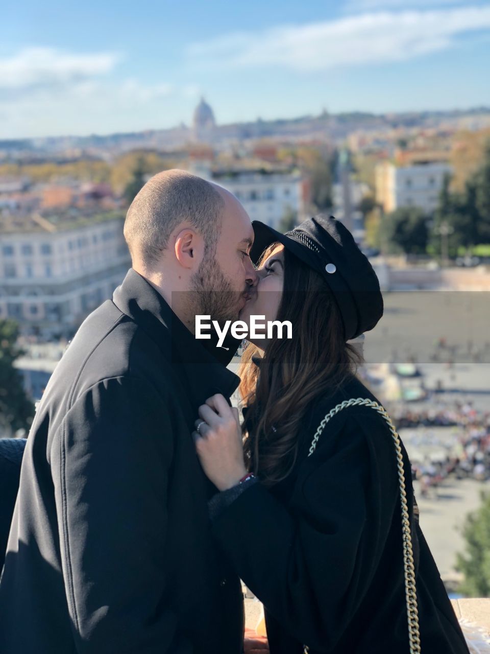 Side view of young couple kissing while standing in city