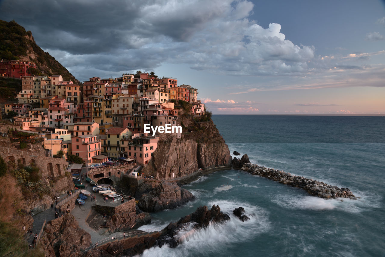 Scenic view of sea by manarola buildings against sky, in cinqueterre