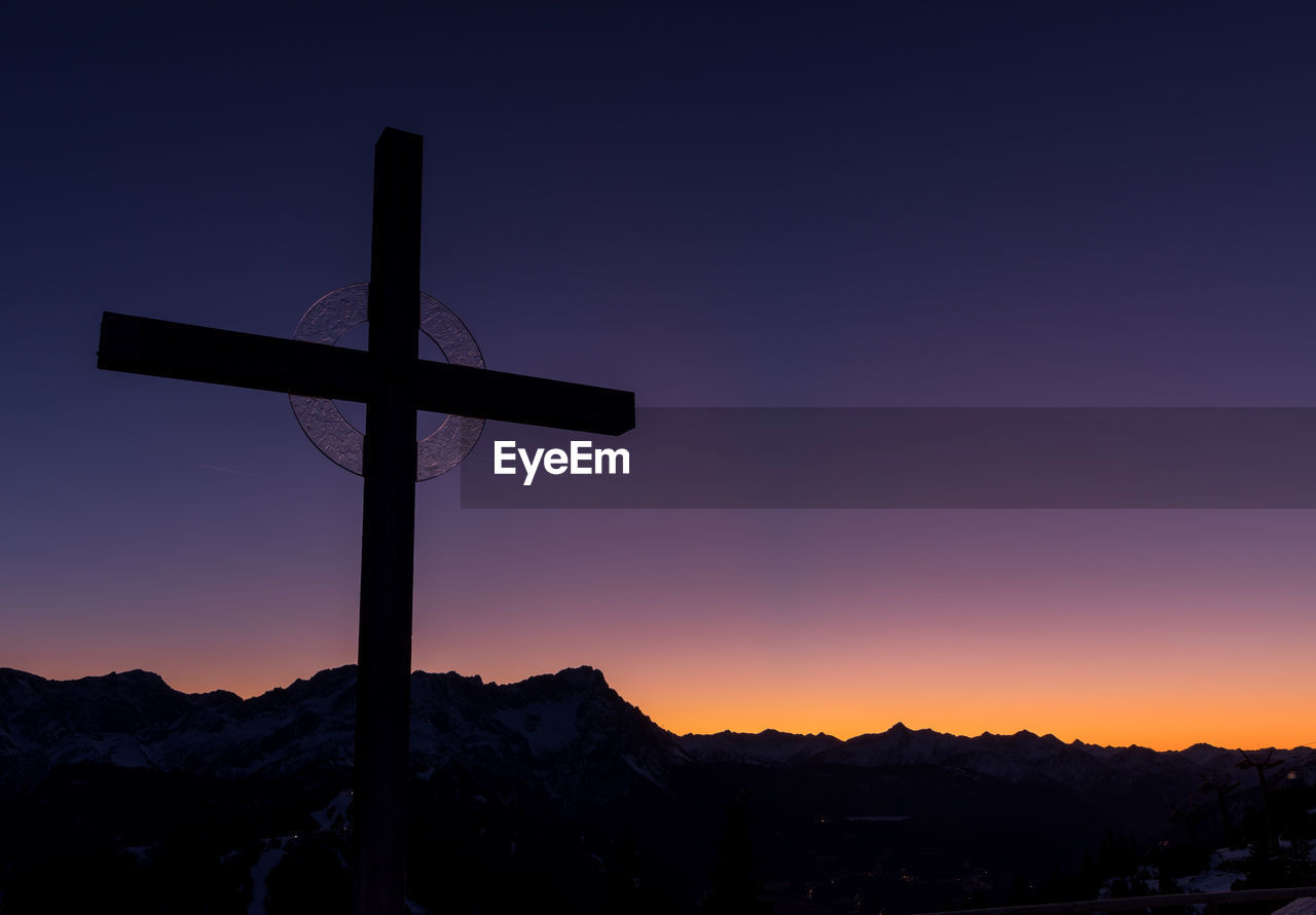 Silhouette cross against sky during sunset