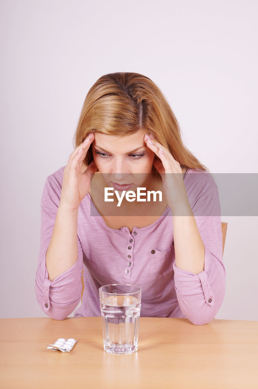 Young woman with headaches against white background