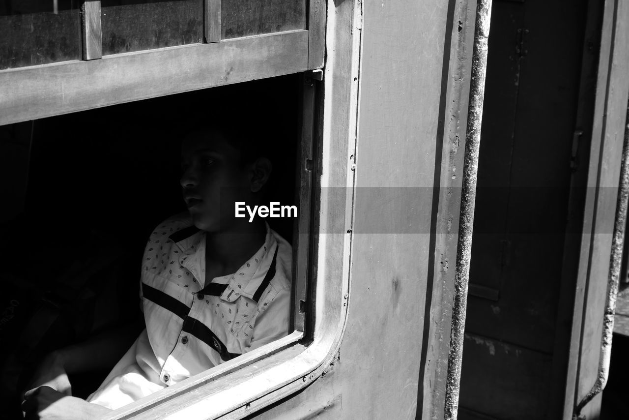 Young man sitting in train seen through window