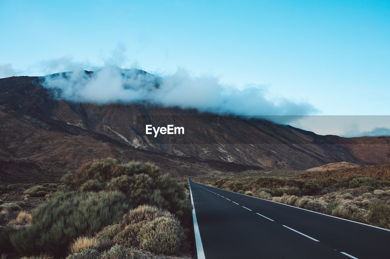 Scenic view of road by mountains against sky