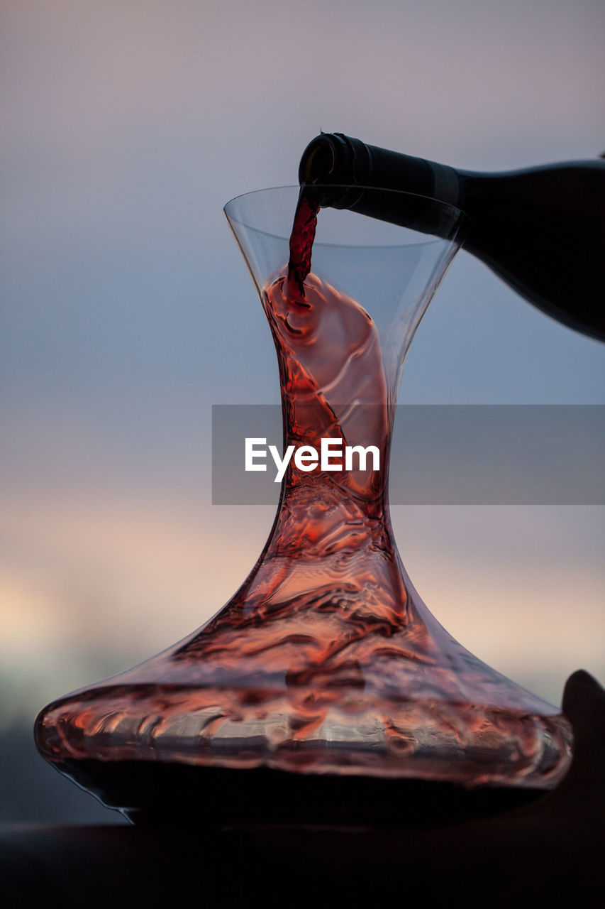 Cropped image of bottle pouring red wine in decanter