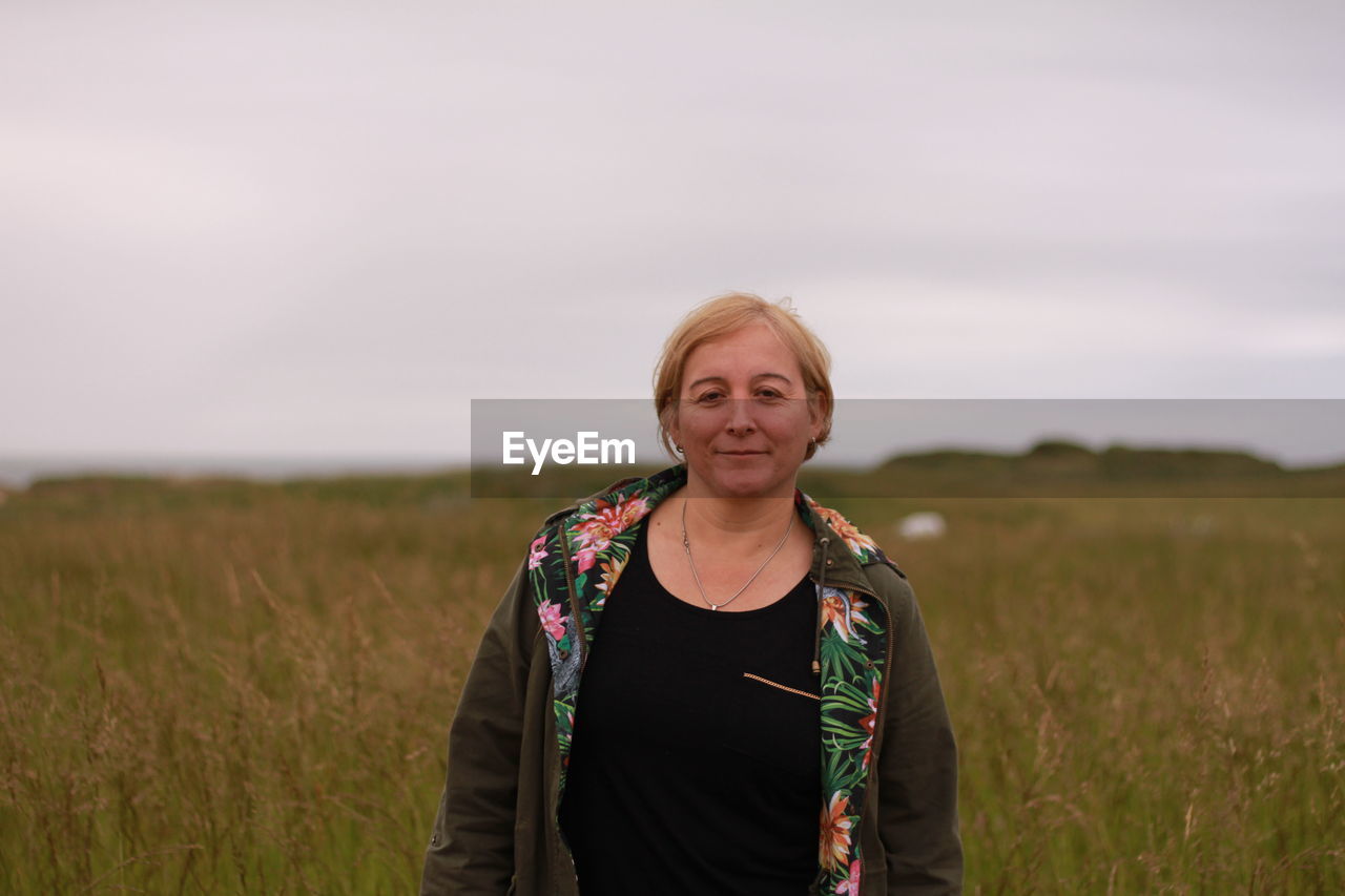 Portrait of smiling young woman standing on field