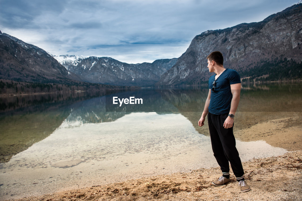 Man standing by lake against mountains