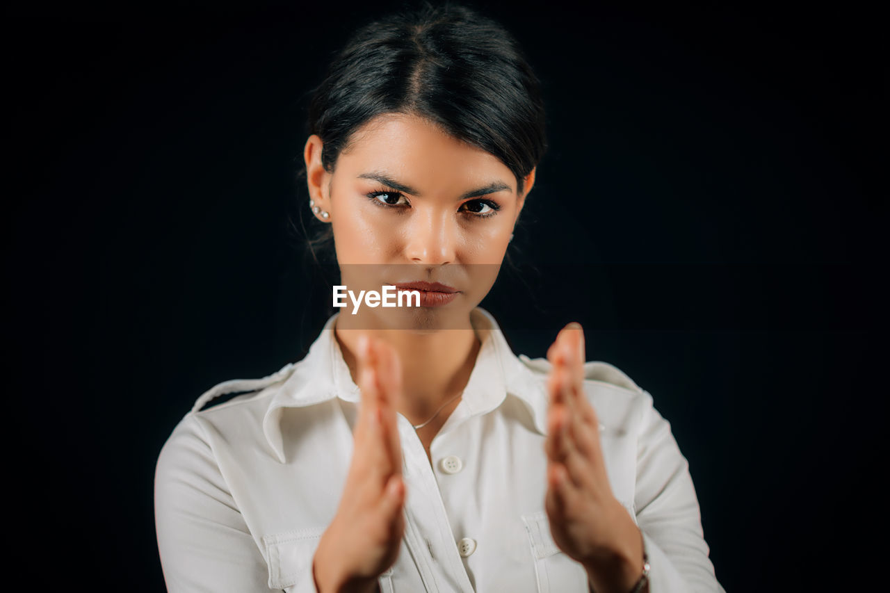 PORTRAIT OF A YOUNG WOMAN AGAINST BLACK BACKGROUND