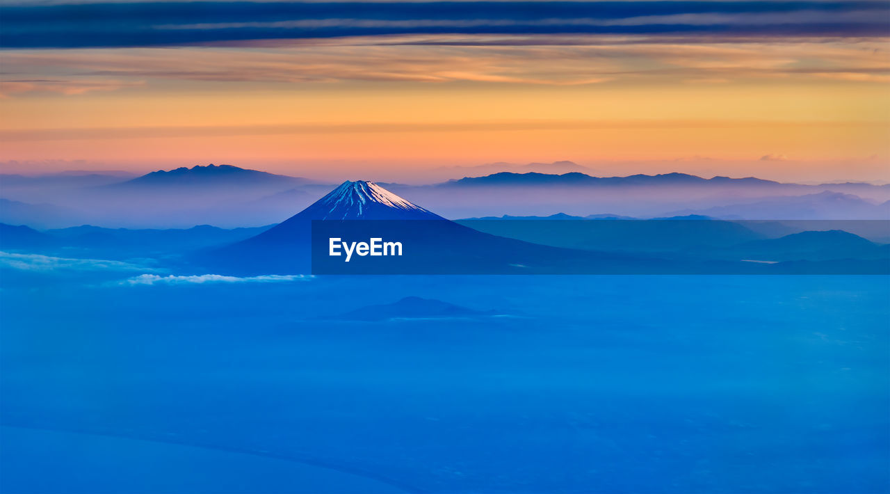 AERIAL VIEW OF SNOWCAPPED MOUNTAIN AGAINST CLOUDY SKY