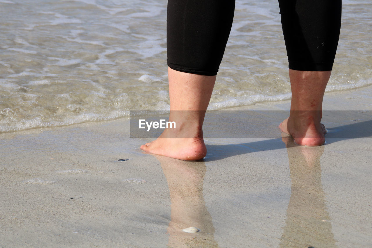 LOW SECTION OF MAN STANDING ON SHORE