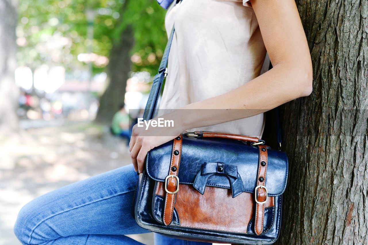 Midsection of woman with leather bag