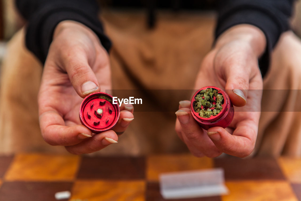 Midsection of man holding cannabis in container