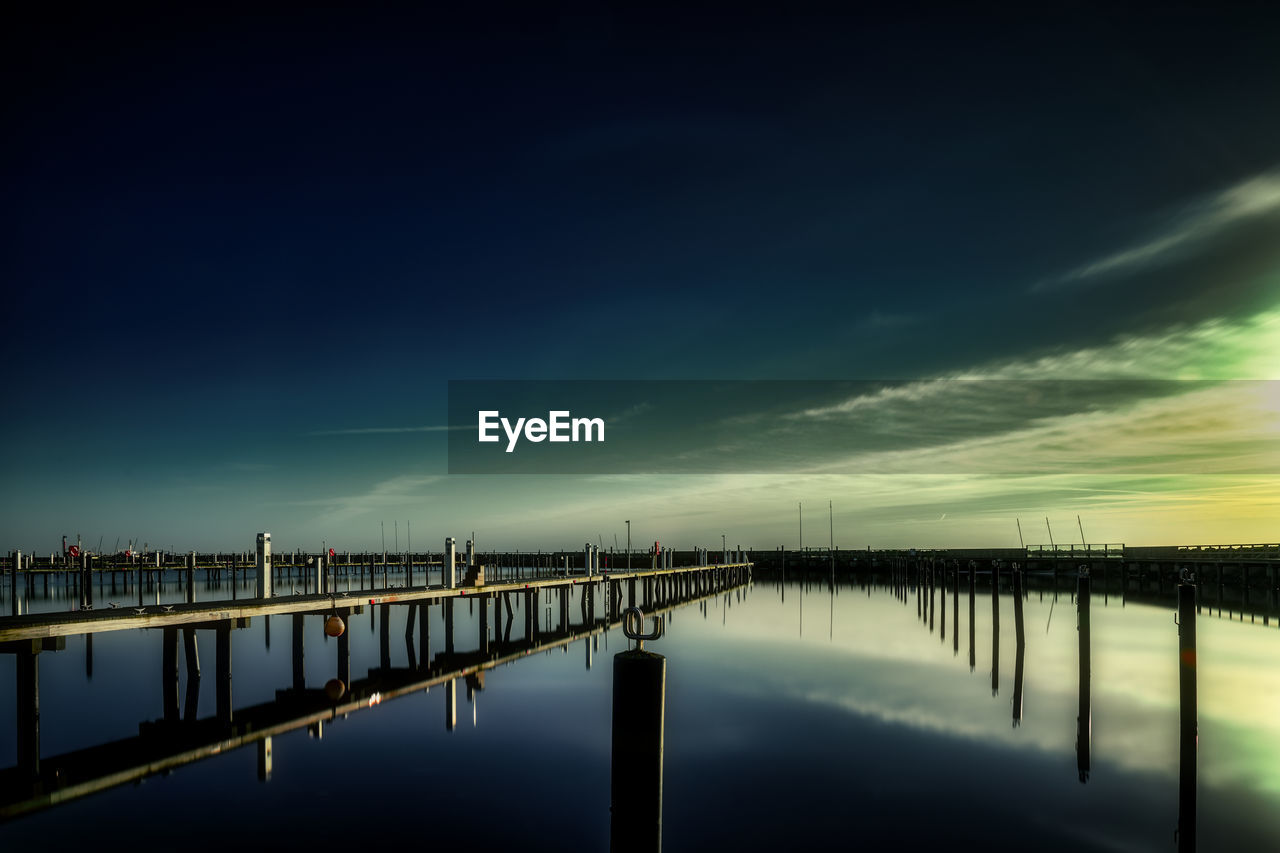 pier over lake against sky at sunset