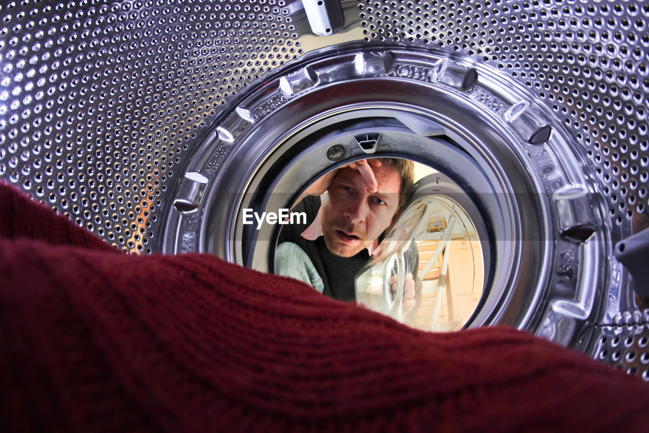 Portrait of man seen through washing machine