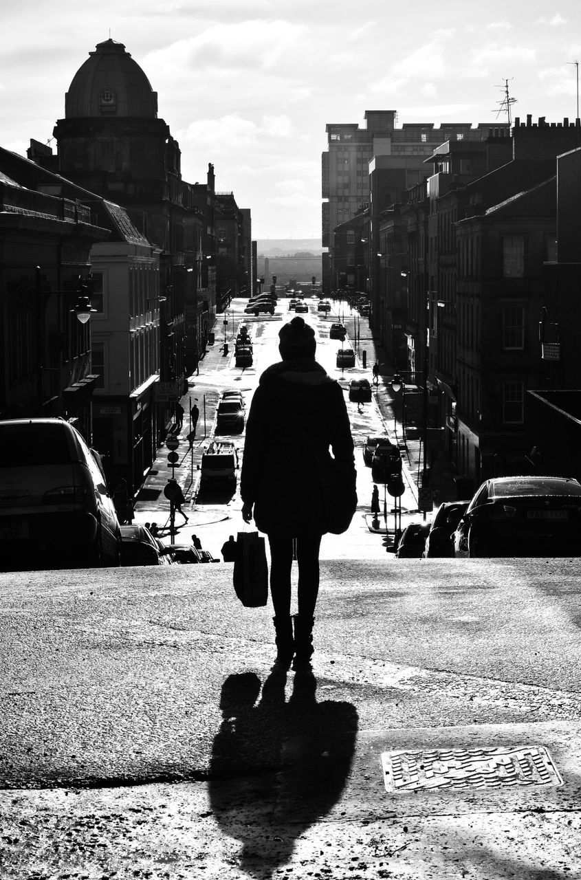 Rear view of woman standing on street in city