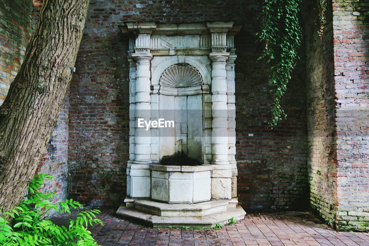 Old fountain by brick wall