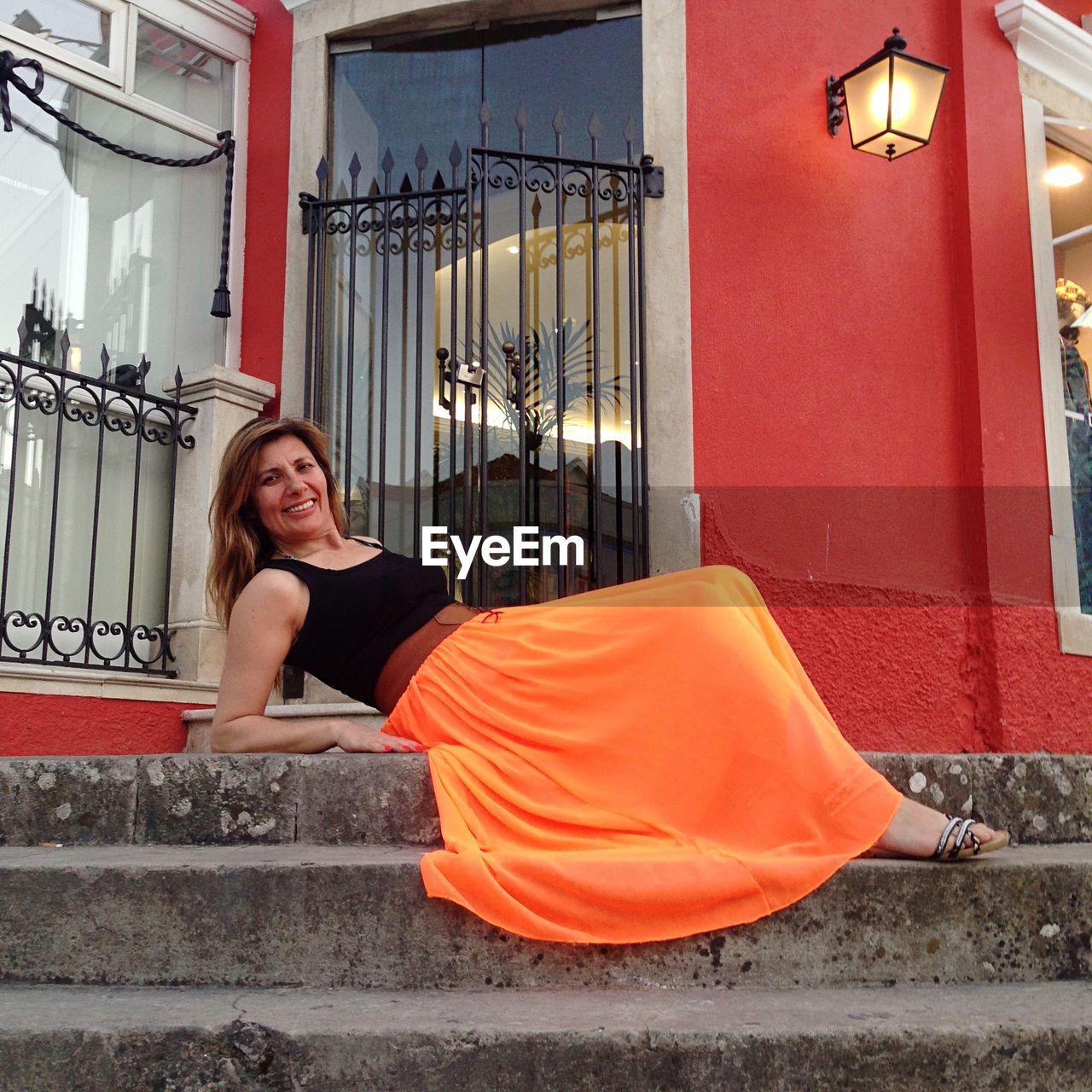 Portrait of smiling woman sitting on steps of building