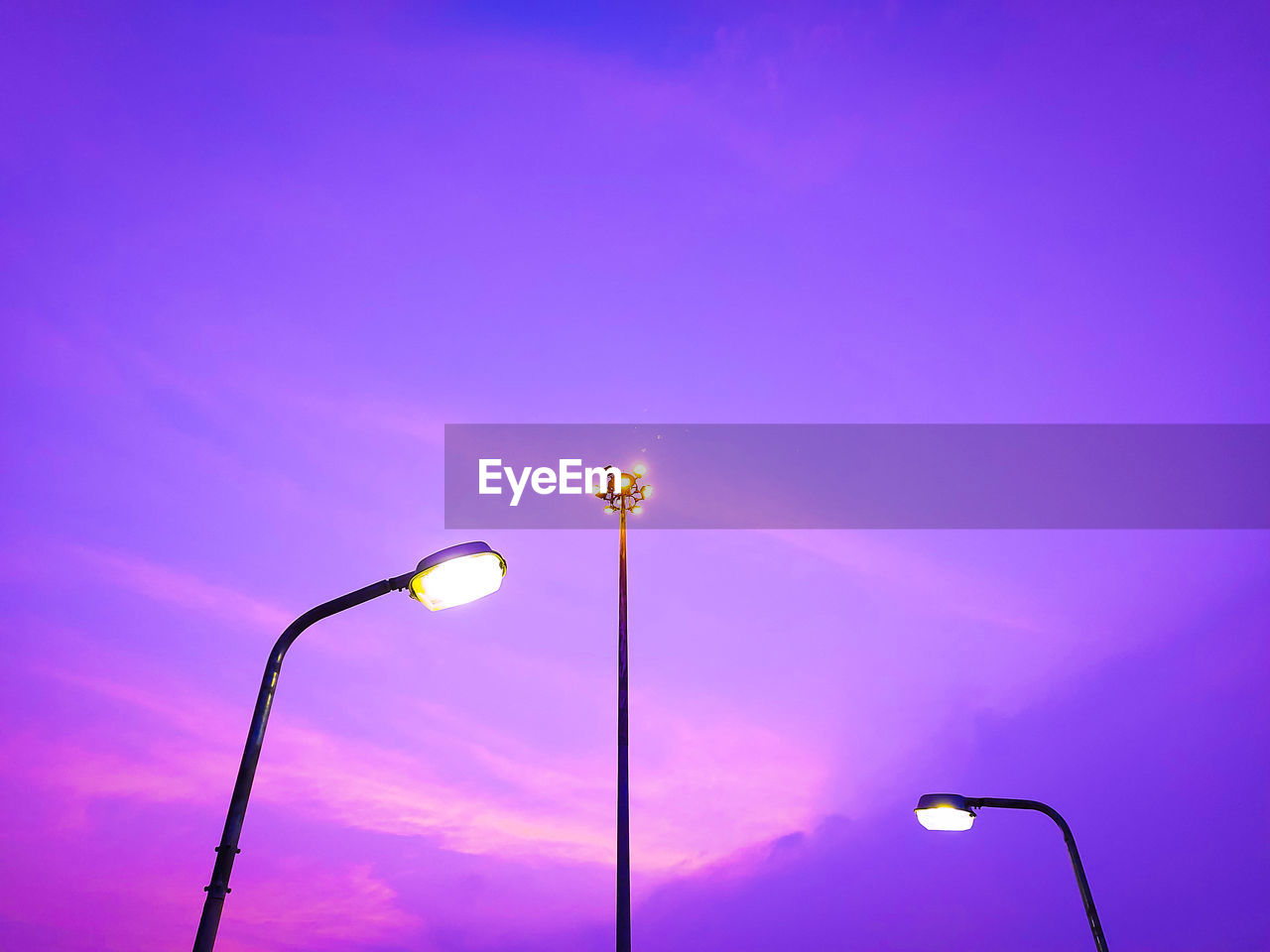 Low angle view of illuminated street light against blue sky