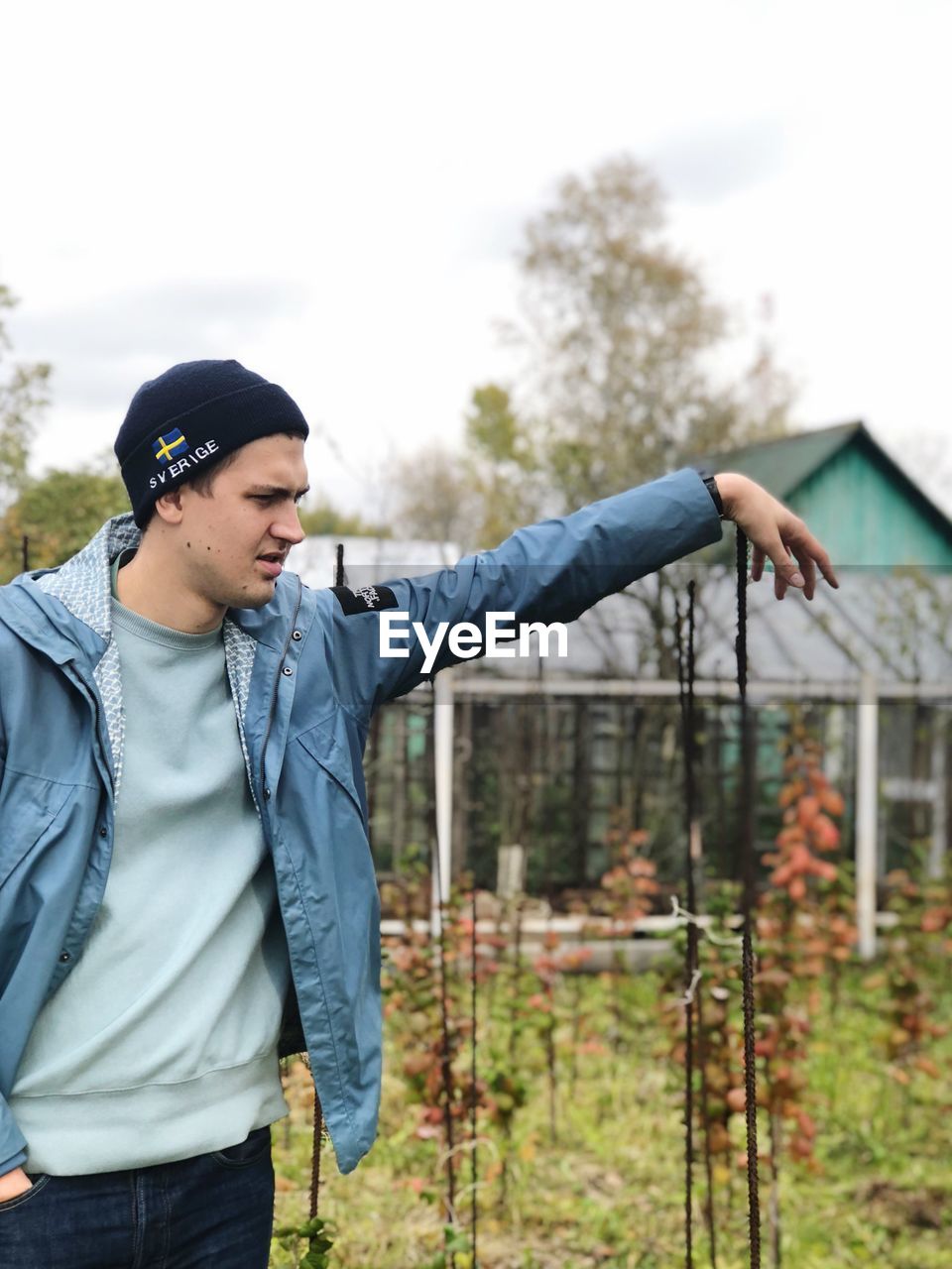 Young man wearing jacket looking away while standing on land